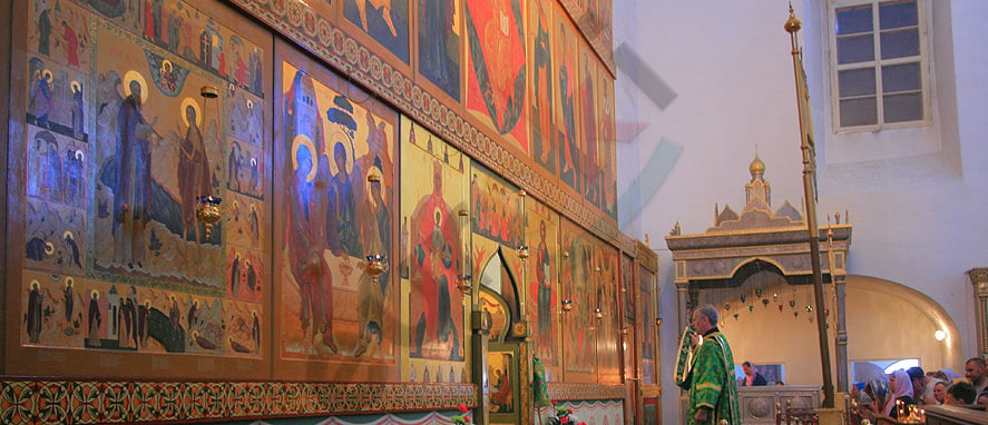 A person standing in front of a wall with religious paintings Description automatically generated